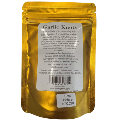 A 35g Shrimp Envy stand-up pouch of 'Garlic Knots' shrimp pellets, showing the back of the packaging with product details, ingredients, and instructions on a white background.